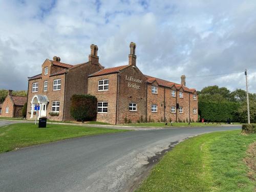 un gran edificio de ladrillo al lado de una carretera en Loftsome Bridge Hotel en Wressell