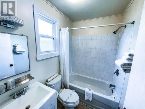 a bathroom with a toilet and a tub and a sink at Tantramar Motel in Sackville