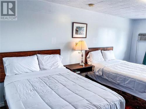 una camera d'albergo con due letti e un tavolo con una lampada di Tantramar Motel a Sackville