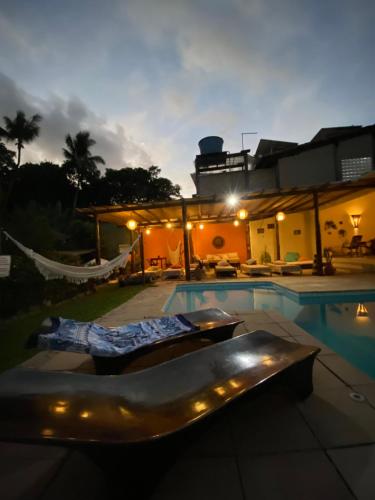 a swimming pool with a hammock next to a house at Pousada Tubarão in Arraial d'Ajuda
