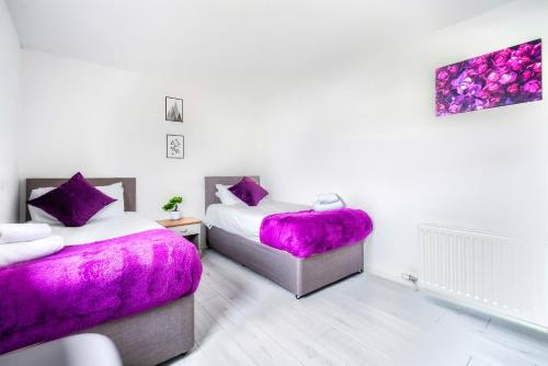 2 camas en una habitación con almohadas moradas en Balloch House -Spacious 3 bed house with on street parking en Kirk of Shotts