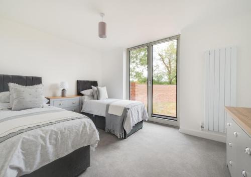 a white bedroom with two beds and a window at Abbey View in Leiston