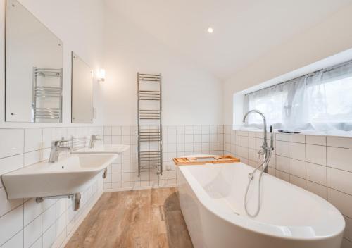 a white bathroom with two sinks and a window at Abbey View in Leiston