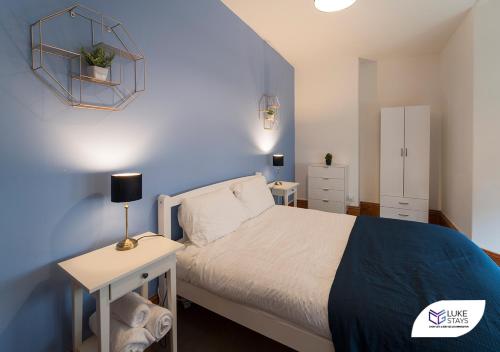 a bedroom with a bed and a blue wall at Luke Stays - Grosvenor Road in Jesmond