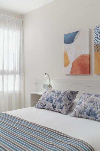 a white bed with two pillows in a bedroom at Las Afortunadas - Playa Arinaga 2ºD in Arinaga