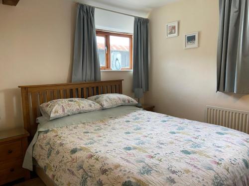 a bedroom with a bed and a window at Tupenny Cottage, Old Mill Farm, Cotswold Water Park in Cirencester