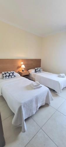 a room with two beds with white sheets at APARTAMENTOS TURÍSTICOS CASA SANDRA in Sanxenxo
