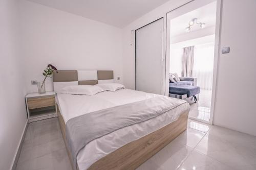 a white bedroom with a large bed and a mirror at The moon in Sandanski
