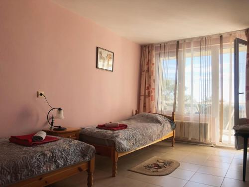 a bedroom with two beds and a large window at Guest House Paskal in Balchik