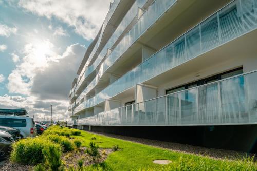 a building with cars parked in a parking lot at POLANKI AQUA Apartamenty PREMIUM - w cenie nielimitowany dostęp do strefy Aqua in Kołobrzeg