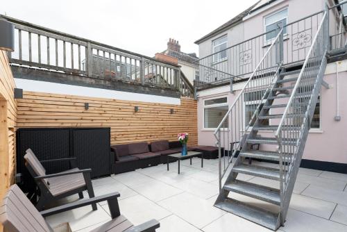 a patio with a couch and a spiral stair case at MORLANOW-Private entrance, courtyard, sea views in Newquay