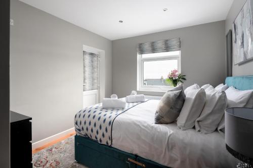 a bedroom with a bed with white pillows and a window at MORLANOW-Private entrance, courtyard, sea views in Newquay