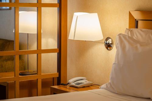 a bed with a lamp and a phone on a table at Hotel Roma in Lisbon