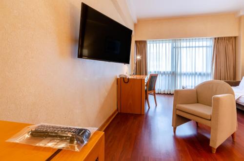 a hotel room with a couch and a television on the wall at Hotel Roma in Lisbon