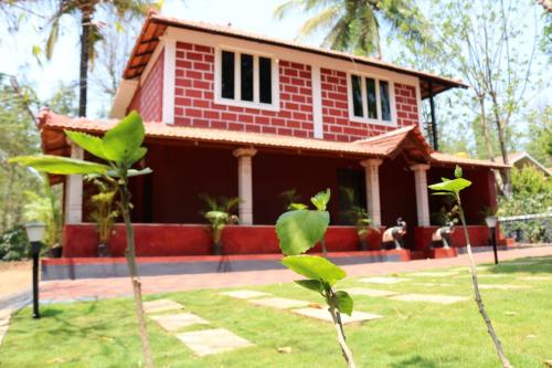 a red house with a tree in front of it at D signature Homestay By Lexstays in Kushālnagar