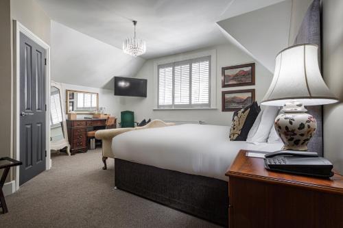 a bedroom with a bed and a desk with a lamp at Forest Park Country Hotel & Inn, Brockenhurst, New Forest, Hampshire in Brockenhurst