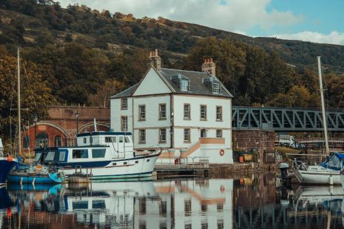 Ein Boot liegt neben einem Haus im Wasser vor Anker. in der Unterkunft Custom House Hotel in Bowling