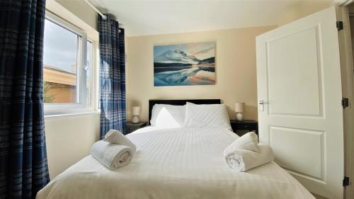 a bedroom with a bed with white sheets and a window at Broad Gauge Apartments in Wolverhampton