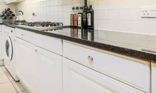 cocina con armarios blancos y encimera en City Riverview 1/2 Bedroom Apartment en Londres