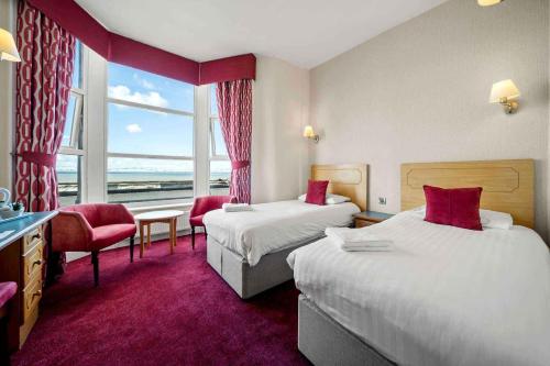 a hotel room with two beds and a window at Claremont Hotel in Blackpool