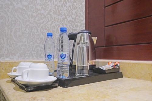 - un comptoir avec 2 bouteilles d'eau et une cafetière dans l'établissement EKONO by Leva Jeddah Airport Hotel, à Djeddah