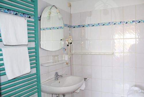 ein weißes Badezimmer mit einem Waschbecken und einem Spiegel in der Unterkunft Schlossberghof Marzoll in Bad Reichenhall
