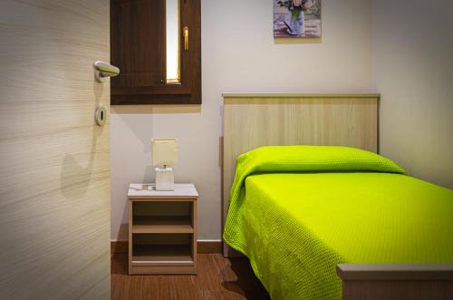 a bedroom with a green bed and a night stand at La casa di Bice in Cassibile