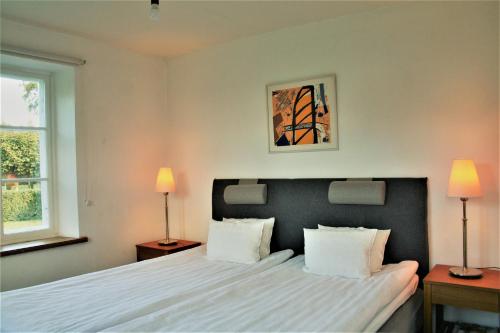 a bedroom with a white bed with two lamps at Hoby Gård in Borrby