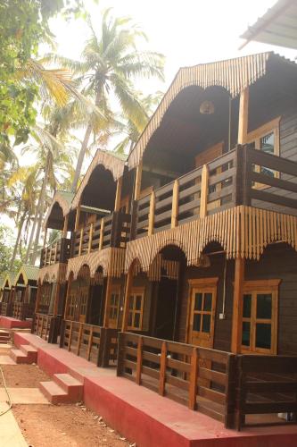 a building with a fence and palm trees in the background at LOTUS feet BEACH RESORT Morjim in Morjim