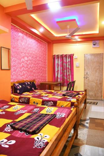 a bedroom with two beds and a wall with purple at Anandi Nivas in Talavda