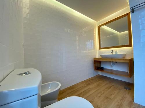 a bathroom with a white toilet and a sink at Nature & Sea - Casa da Vinhateira South in Caloura