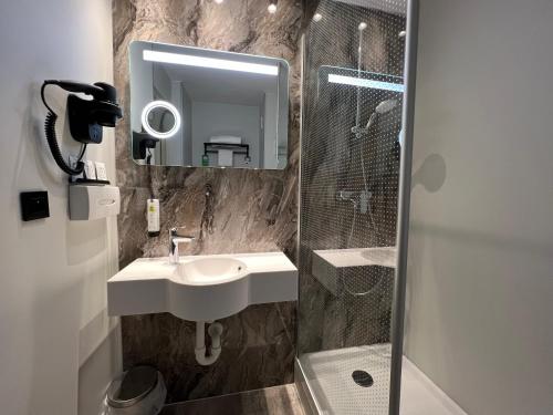 a bathroom with a sink and a shower and a mirror at Logis Hôtel Restaurant Des Acacias Lille Tourcoing in Neuville-en-Ferrain