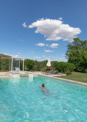 a man in a swimming pool with a cloud in the sky at Mas Coeur Provence Calme Beauté Grand Parc in Pernes-les-Fontaines