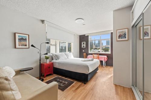 a bedroom with a bed and a couch at BROUG10W - City View Studio in Sydney