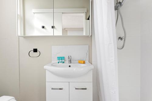 a white bathroom with a sink and a shower at BROUG10W - City View Studio in Sydney