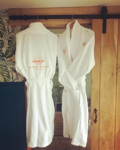 two white robes are hanging on a door at The Caswell bay hide out in Swansea