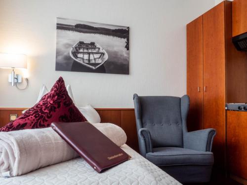 a bed with a book on it next to a chair at Garni Hotel & Appartements Nordstrand in Nordstrand