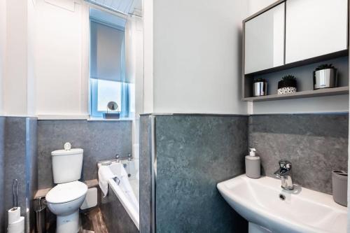 a bathroom with a toilet and a sink and a mirror at Kali Apartment - Spacious 3 bed apartment in Wishaw in Wishaw