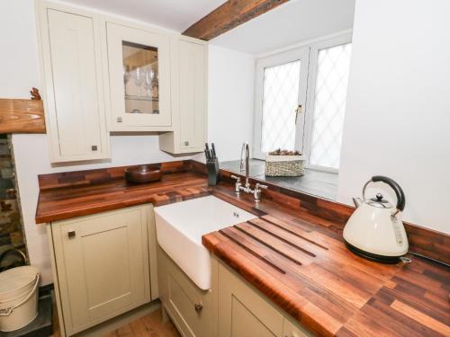 a kitchen with white cabinets and a wooden counter top at Dove Cottage in Abergele