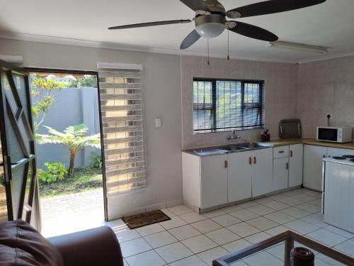 a kitchen with white cabinets and a ceiling fan at Bujumbura Guest House in Port Edward