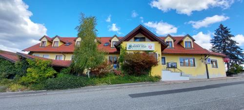 uma casa amarela com um telhado vermelho numa rua em Landrasthaus Maria Bild em Maria Bild
