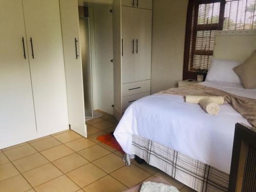 a bedroom with a bed and white cabinets and a tiled floor at Bujumbura Guest House in Port Edward