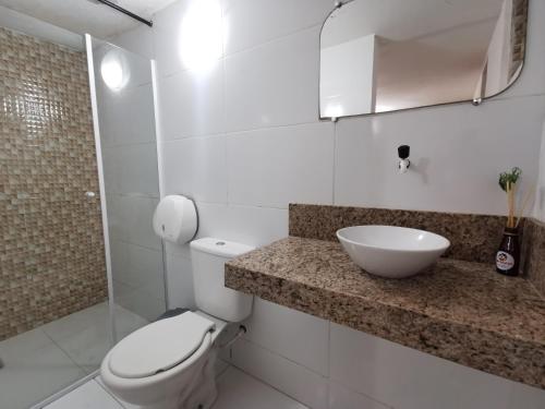 Un baño blanco con inodoro y lavabo. en Sos Hostel, en Camaçari