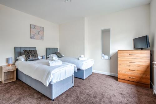 a bedroom with two beds and a tv and a dresser at Millfield House - Cosy 2 bed house in Motherwell in Motherwell