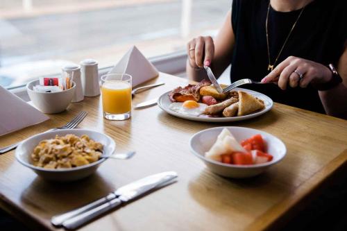 a woman sitting at a table with plates of breakfast food at Viking Hotel - Adults Only in Blackpool