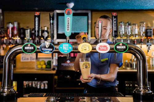 a man is holding a drink behind a bar at Viking Hotel - Adults Only in Blackpool