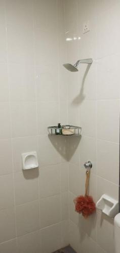a white tiled bathroom with a sink and a shower at 7eVenKitchen Hmestay in Jitra