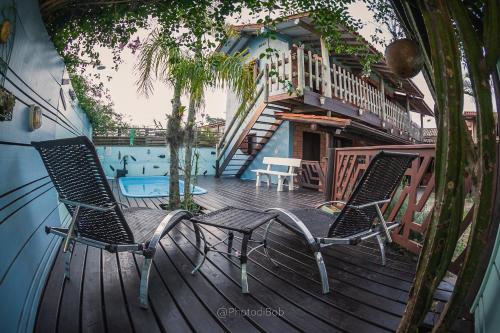 two chairs sitting on a deck with a swimming pool at Pousada Amaravida in Praia do Rosa
