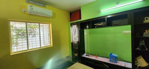 a room with a green wall with a large screen television at JJ's White House in Trichūr