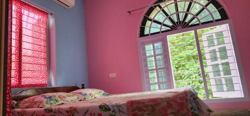 a bedroom with pink walls and a bed and two windows at JJ's White House in Trichūr